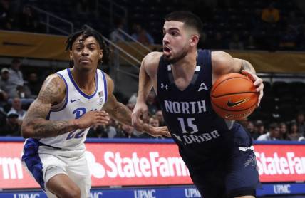 Dec 17, 2022; Pittsburgh, Pennsylvania, USA; North Florida Ospreys guard Jose Placer (15) dribbles the ball against Pittsburgh Panthers guard Nike Sibande (22) during the first half at the Petersen Events Center. Mandatory Credit: Charles LeClaire-USA TODAY Sports