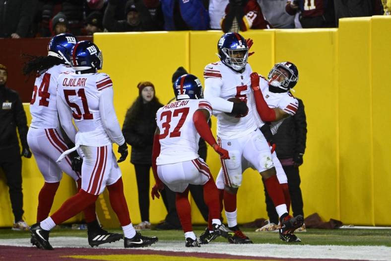 Dec 18, 2022; Landover, Maryland, USA; New York Giants defensive end Kayvon Thibodeaux (5) is congratulated by teammates after scoring a touchdown  against the Washington Commanders during the first half at FedExField. Mandatory Credit: Brad Mills-USA TODAY Sports