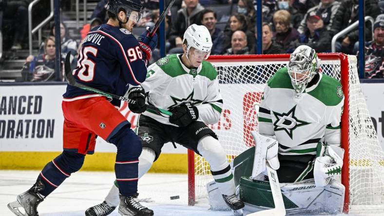 Dec 19, 2022; Columbus, Ohio, USA; Dallas Stars goaltender Jake Oettinger (29) makes a save with Columbus Blue Jackets center Jack Roslovic (96) and Stars defenseman Nils Lundkvist (5) in the crease in the first period at Nationwide Arena. Mandatory Credit: Gaelen Morse-USA TODAY Sports