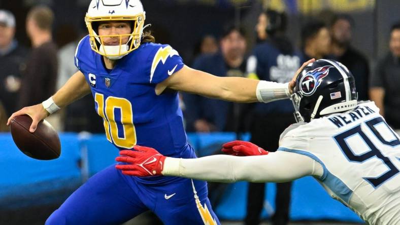 Dec 18, 2022; Inglewood, California, USA; Los Angeles Chargers quarterback Justin Herbert (10) and Tennessee Titans linebacker Rashad Weaver (99) during the fourth quarter at SoFi Stadium. Mandatory Credit: Robert Hanashiro-USA TODAY Sports