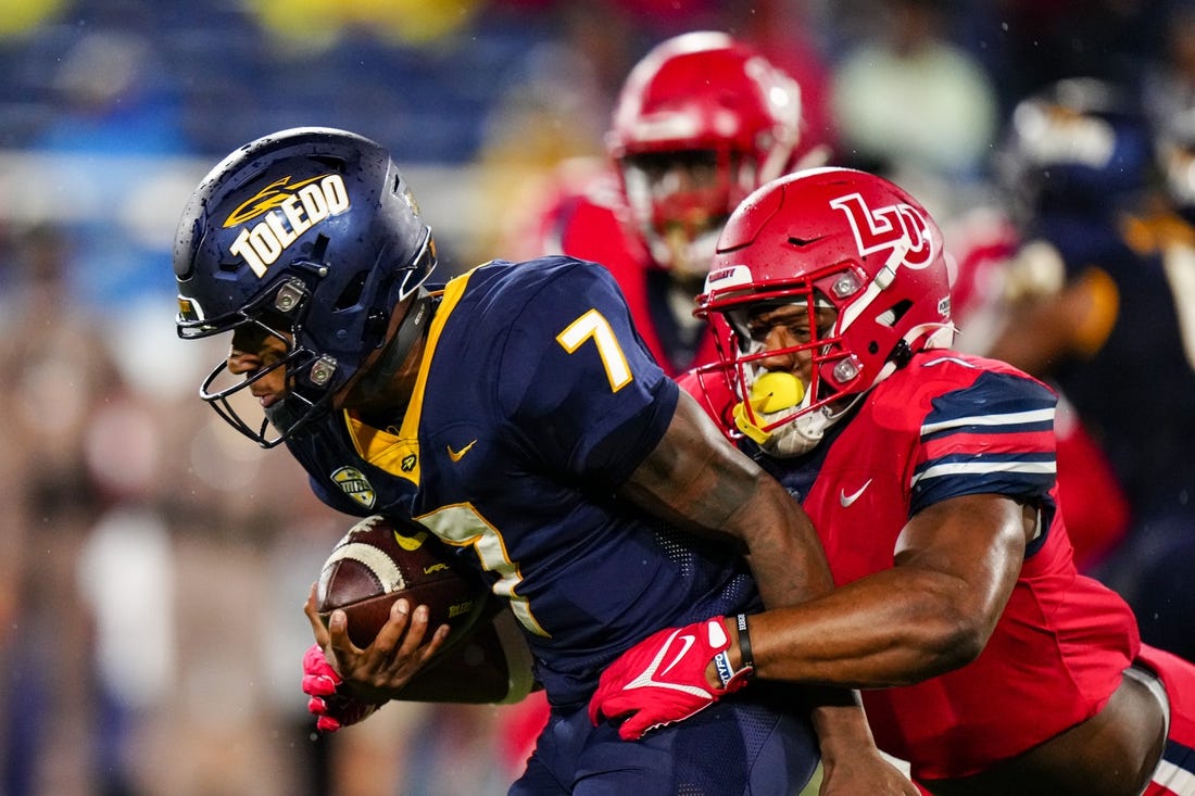 Dec 20, 2022; Boca Raton, Florida, USA; Liberty Flames linebacker Mike Smith Jr. (7) tackles Toledo Rockets quarterback Dequan Finn (7) during the first quarter in the 2022 Boca Raton Bowl at FAU Stadium. Mandatory Credit: Rich Storry-USA TODAY Sports