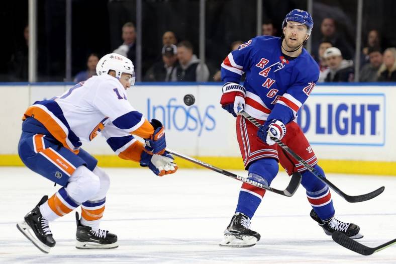 Dec 22, 2022; New York, New York, USA; New York Rangers center Barclay Goodrow (21) plays the puck past New York Islanders left wing Zach Parise (11) during the second period at Madison Square Garden. Mandatory Credit: Brad Penner-USA TODAY Sports