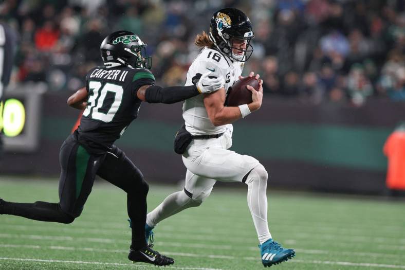 Dec 22, 2022; East Rutherford, New Jersey, USA; Jacksonville Jaguars quarterback Trevor Lawrence (16) carries the ball as New York Jets cornerback Michael Carter II (30) attempts to tackle during the first half at MetLife Stadium. Mandatory Credit: Vincent Carchietta-USA TODAY Sports