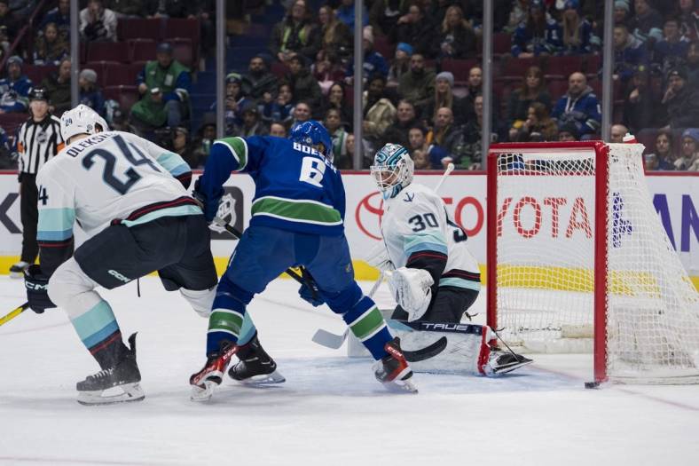 Dec 22, 2022; Vancouver, British Columbia, CAN; Seattle Kraken defenseman Jamie Oleksiak (24) and goalie Martin Jones (30) and Vancouver Canucks forward Brock Boeser (6) watch the puck hits the post in the first period at Rogers Arena. Mandatory Credit: Bob Frid-USA TODAY Sports