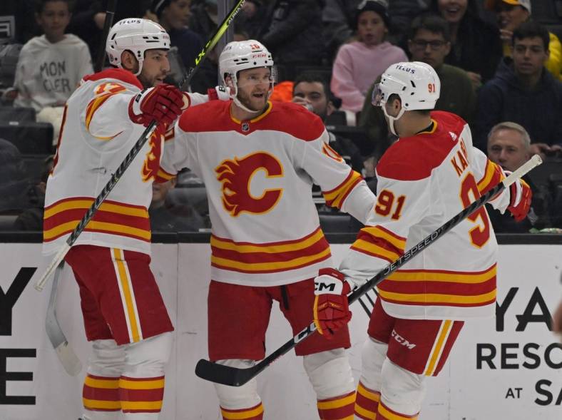 Dec 22, 2022; Los Angeles, California, USA; Calgary Flames center Jonathan Huberdeau (10) is congratulated by left wing Milan Lucic (17) and center Nazem Kadri (91) after scoring a goal in the first period against the Los Angeles Kings at Crypto.com Arena. Mandatory Credit: Jayne Kamin-Oncea-USA TODAY Sports