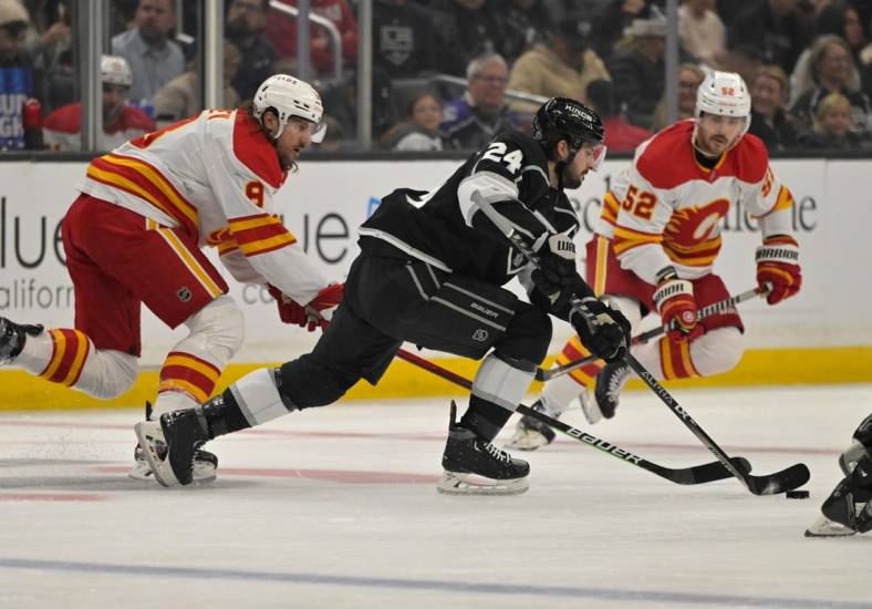 Dec 22, 2022; Los Angeles, California, USA; Los Angeles Kings center Phillip Danault (24) takes the puck past Calgary Flames defenseman Chris Tanev (8) in the first period at Crypto.com Arena. Mandatory Credit: Jayne Kamin-Oncea-USA TODAY Sports