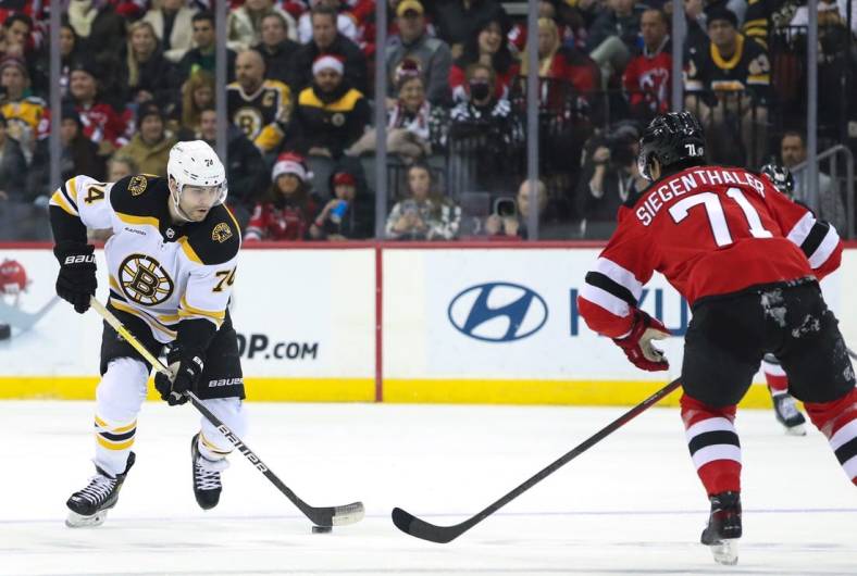 Dec 23, 2022; Newark, New Jersey, USA;  Boston Bruins left wing Jake DeBrusk (74) skates up ice while New Jersey Devils defenseman Jonas Siegenthaler (71) pursues during the first period at Prudential Center. Mandatory Credit: Thomas Salus-USA TODAY Sports