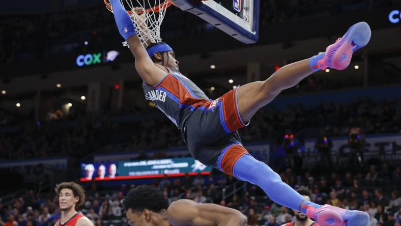 Dec 23, 2022; Oklahoma City, Oklahoma, USA; Oklahoma City Thunder guard Shai Gilgeous-Alexander (2) hangs on the basket after dunking against the New Orleans Pelicans during the second quarter at Paycom Center. Mandatory Credit: Alonzo Adams-USA TODAY Sports