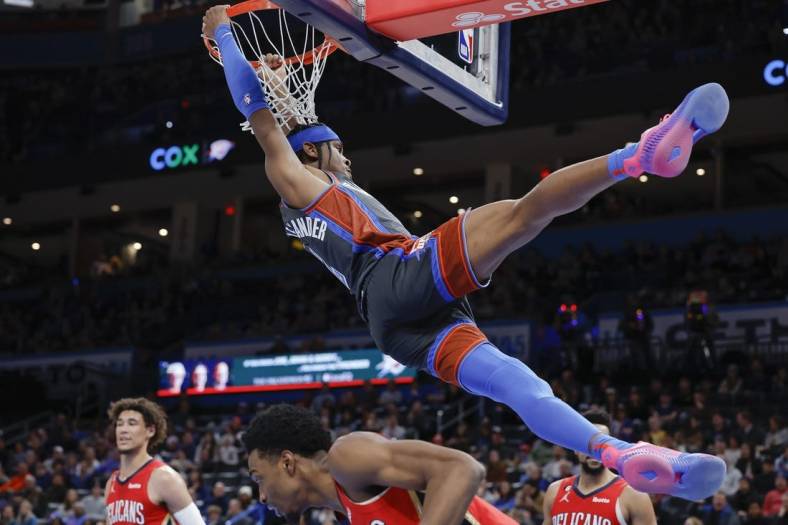 Dec 23, 2022; Oklahoma City, Oklahoma, USA; Oklahoma City Thunder guard Shai Gilgeous-Alexander (2) hangs on the basket after dunking against the New Orleans Pelicans during the second quarter at Paycom Center. Mandatory Credit: Alonzo Adams-USA TODAY Sports