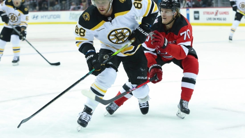 Dec 23, 2022; Newark, New Jersey, USA;  Boston Bruins right wing David Pastrnak (88) controls the puck while New Jersey Devils center Jesper Boqvist (70) defends during the first period at Prudential Center. Mandatory Credit: Thomas Salus-USA TODAY Sports