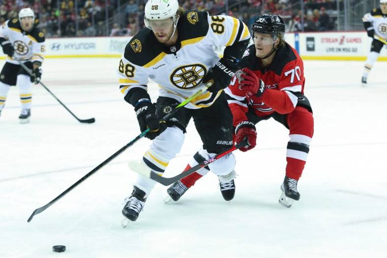 Dec 23, 2022; Newark, New Jersey, USA;  Boston Bruins right wing David Pastrnak (88) controls the puck while New Jersey Devils center Jesper Boqvist (70) defends during the first period at Prudential Center. Mandatory Credit: Thomas Salus-USA TODAY Sports