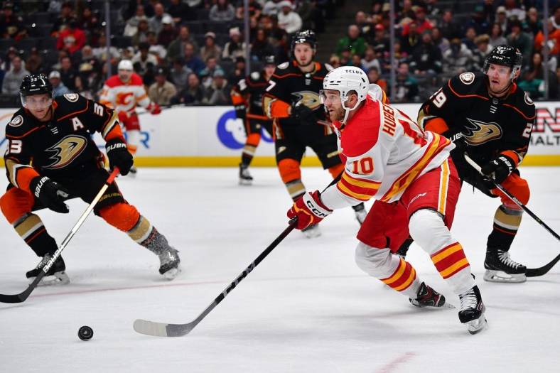 Dec 23, 2022; Anaheim, California, USA; Calgary Flames center Jonathan Huberdeau (10) controls the puck against Anaheim Ducks defenseman Dmitry Kulikov (29) and right wing Jakob Silfverberg (33) during the first period at Honda Center. Mandatory Credit: Gary A. Vasquez-USA TODAY Sports