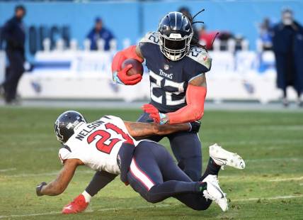 Dec 24, 2022; Nashville, Tennessee, USA; Tennessee Titans running back Derrick Henry (22) fights off a tackle attempt from Houston Texans cornerback Steven Nelson (21) during the second half at Nissan Stadium. Mandatory Credit: Christopher Hanewinckel-USA TODAY Sports