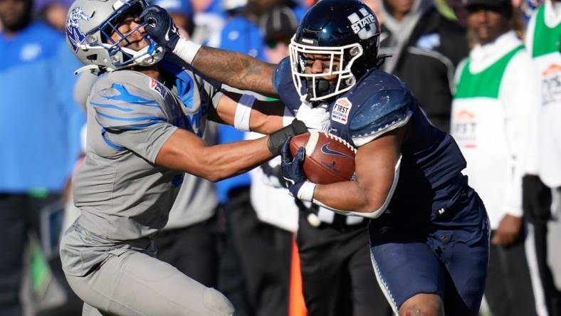 Dec 27, 2022; Dallas, Texas, USA; Utah State Aggies running back Calvin Tyler Jr. (4) breaks a tackle against Memphis Tigers linebacker Geoffrey Cantin-Arku (9) during the first half of the 2022 First Responder Bowl at Gerald J. Ford Stadium. Mandatory Credit: Chris Jones-USA TODAY Sports