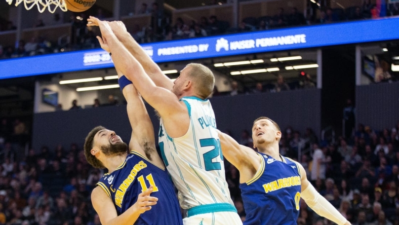 Dec 27, 2022; San Francisco, California, USA; Charlotte Hornets forward Mason Plumlee (24) knocks away a rebound between Golden State Warriors guards Klay Thompson (11) and Donte DiVincenzo (0) during the second quarter at Chase Center. Mandatory Credit: D. Ross Cameron-USA TODAY Sports