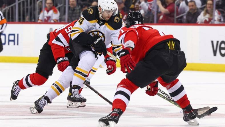 Dec 28, 2022; Newark, New Jersey, USA; Boston Bruins left wing Jake DeBrusk (74) skates with the puck while being defended by New Jersey Devils defenseman Jonas Siegenthaler (71) during the first period at Prudential Center. Mandatory Credit: Ed Mulholland-USA TODAY Sports