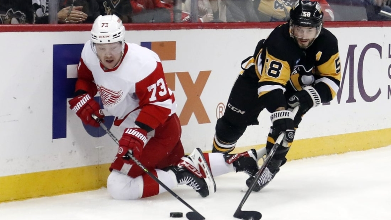 Dec 28, 2022; Pittsburgh, Pennsylvania, USA;  Detroit Red Wings left wing Adam Erne (73) reaches for the puck against Pittsburgh Penguins defenseman Kris Letang (58) during the first period at PPG Paints Arena. Mandatory Credit: Charles LeClaire-USA TODAY Sports
