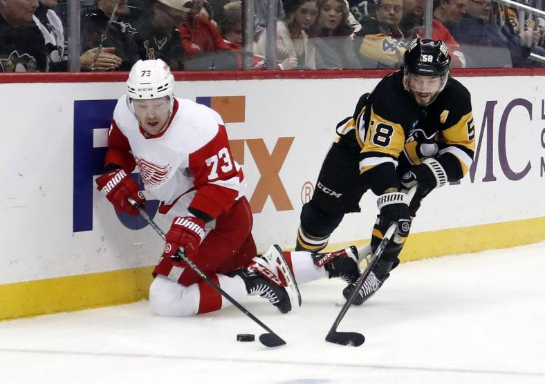 Dec 28, 2022; Pittsburgh, Pennsylvania, USA;  Detroit Red Wings left wing Adam Erne (73) reaches for the puck against Pittsburgh Penguins defenseman Kris Letang (58) during the first period at PPG Paints Arena. Mandatory Credit: Charles LeClaire-USA TODAY Sports