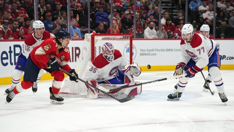 Dec 29, 2022; Sunrise, Florida, USA; Florida Panthers left wing Ryan Lomberg (94) and Montreal Canadiens center Kirby Dach (77) battle for a loose puck in front of Montreal Canadiens goaltender Sam Montembeault (35) during the second period period at FLA Live Arena. Mandatory Credit: Jasen Vinlove-USA TODAY Sports