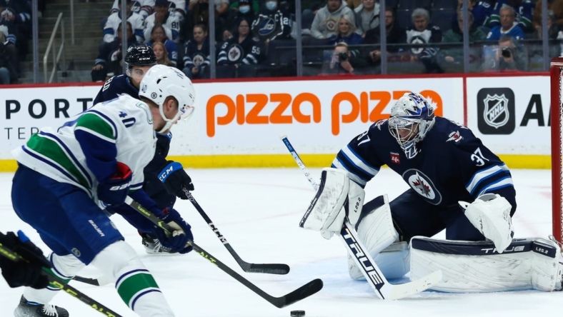 Dec 29, 2022; Winnipeg, Manitoba, CAN;  Winnipeg Jets goalie Connor Hellebuyck (37) watches Vancouver Canucks forward Elias Pettersson (40) during the first period at Canada Life Centre. Mandatory Credit: Terrence Lee-USA TODAY Sports