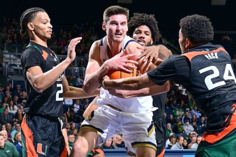 Dec 30, 2022; South Bend, Indiana, USA; Notre Dame Fighting Irish forward Nate Laszewski (14) grabs a rebound in front of Miami Hurricanes guard Isaiah Wong (2) guard Nijel Pack (24) and forward Norchad Omier (15) in the first half at the Purcell Pavilion. Mandatory Credit: Matt Cashore-USA TODAY Sports