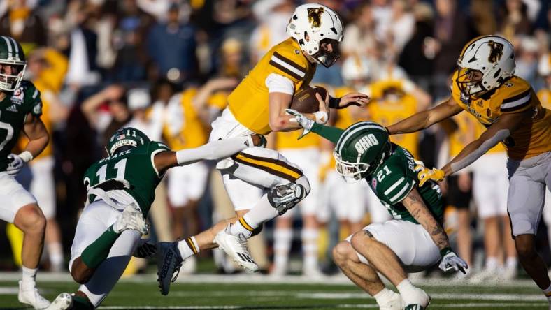 Dec 30, 2022; Tucson, AZ, USA; Wyoming Cowboys quarterback Andrew Peasley (6) runs the ball against Ohio Bobcats safety Tariq Drake (11) and cornerback Austin Brawley (21) in the first half of the 2022 Barstool Sports Arizona Bowl at Arizona Stadium. Mandatory Credit: Mark J. Rebilas-USA TODAY Sports