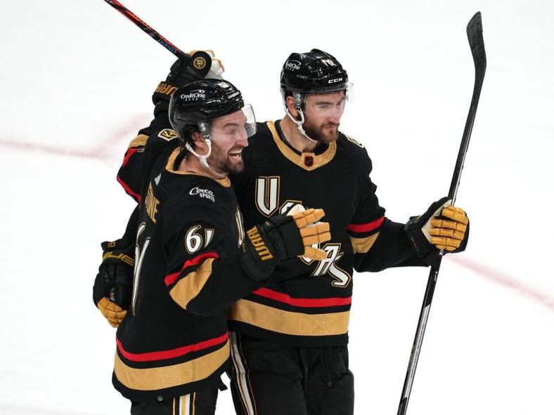 Dec 31, 2022; Las Vegas, Nevada, USA; Vegas Golden Knights right wing Mark Stone (61) and Vegas Golden Knights center Nicolas Roy (10) celebrate after Vegas Golden Knights defenseman Nicolas Hague (14) scored a goal in overtime to give the Golden Knights a 5-4 victory over the Nashville Predators at T-Mobile Arena. Mandatory Credit: Stephen R. Sylvanie-USA TODAY Sports