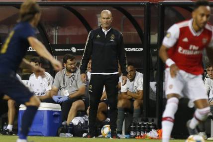 Jul 23, 2019; Landover, MD, USA; Real Madrid head coach Zinedine Zidane (M) looks on from the bench against Arsenal in the second half of a match in the International Champions Cup soccer series at FedEx Field. Real Madrid won 2-2 (3-2 pen.). Mandatory Credit: Geoff Burke-USA TODAY Sports