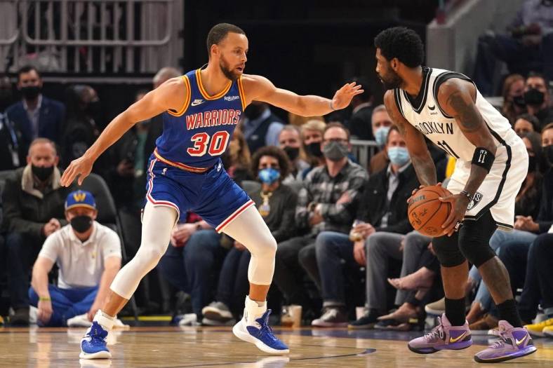 Jan 29, 2022; San Francisco, California, USA; Brooklyn Nets guard Kyrie Irving (11) controls the ball against Golden State Warriors guard Stephen Curry (30) in the first quarter at the Chase Center. Mandatory Credit: Cary Edmondson-USA TODAY Sports