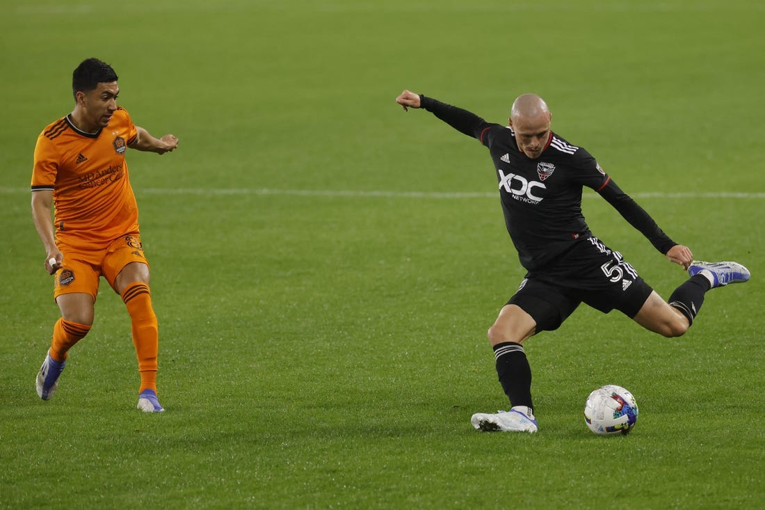 May 7, 2022; Washington, District of Columbia, USA; D.C. United defender Brad Smith (5) crosses the ball as Houston Dynamo midfielder Memo Rodr guez (8) defends in the second half at Audi Field. Mandatory Credit: Geoff Burke-USA TODAY Sports