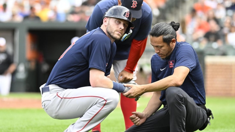Sep 10, 2022; Baltimore, Maryland, USA;  Boston Red Sox second baseman Trevor Story (10) is checked by the team trainer after being hit by a pitch during the first inning against the Baltimore Orioles at Oriole Park at Camden Yards. Mandatory Credit: James A. Pittman-USA TODAY Sports