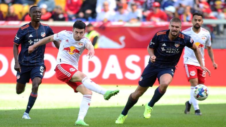 Oct 15, 2022; Harrison, New Jersey, USA;  New York Red Bulls midfielder Lewis Morgan (10) kicks the ball against FC Cincinnati midfielder Obinna Nwobodo (5) and defender Nick Hagglund (4) during the first half at Red Bull Arena. Mandatory Credit: Wendell Cruz-USA TODAY Sports