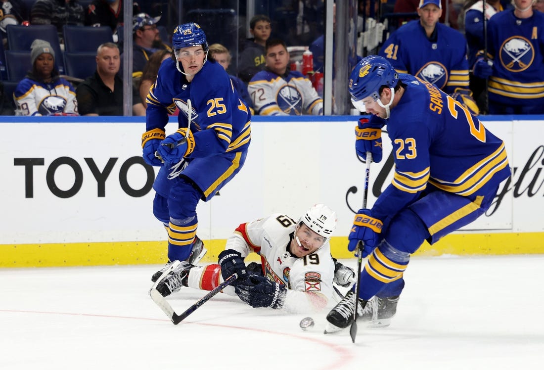 Oct 15, 2022; Buffalo, New York, USA;  Buffalo Sabres defenseman Owen Power (25) watches as Florida Panthers left wing Matthew Tkachuk (19) dives to clear the puck from Buffalo Sabres defenseman Mattias Samuelsson (23) during the third period at KeyBank Center. Mandatory Credit: Timothy T. Ludwig-USA TODAY Sports