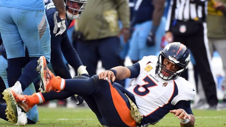 Nov 13, 2022; Nashville, Tennessee, USA; Denver Broncos quarterback Russell Wilson (3) after being hit by Tennessee Titans linebacker Rashad Weaver (99) as he attempts a pass during the second half at Nissan Stadium. Mandatory Credit: Christopher Hanewinckel-USA TODAY Sports