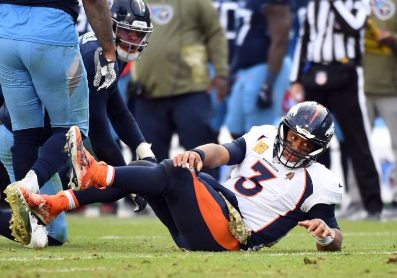Nov 13, 2022; Nashville, Tennessee, USA; Denver Broncos quarterback Russell Wilson (3) after being hit by Tennessee Titans linebacker Rashad Weaver (99) as he attempts a pass during the second half at Nissan Stadium. Mandatory Credit: Christopher Hanewinckel-USA TODAY Sports