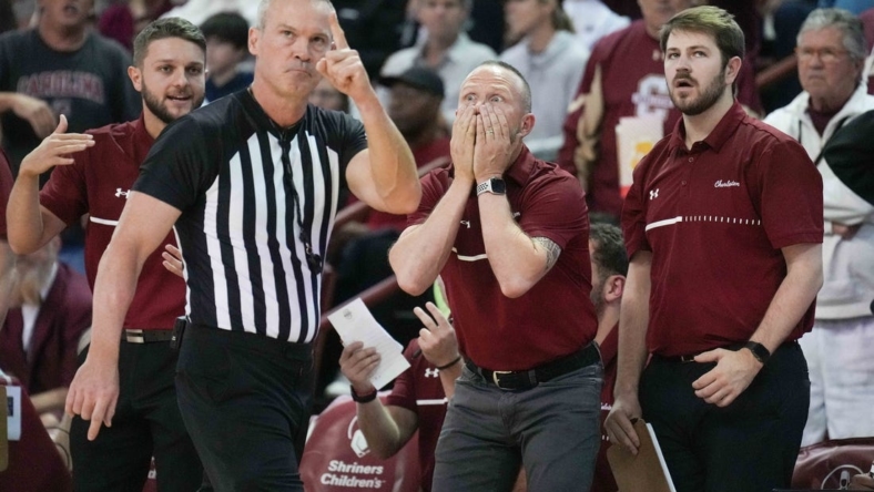 Nov 20, 2022; Charleston, South Carolina, USA; Official Ron Groover (stripes) points to a video board as Charleston Cougars head coach Pat Kelsey reacts in the back ground to a goaltending call in a game against the Virginia Tech Hokies at TD Arena. Mandatory Credit: David Yeazell-USA TODAY Sports