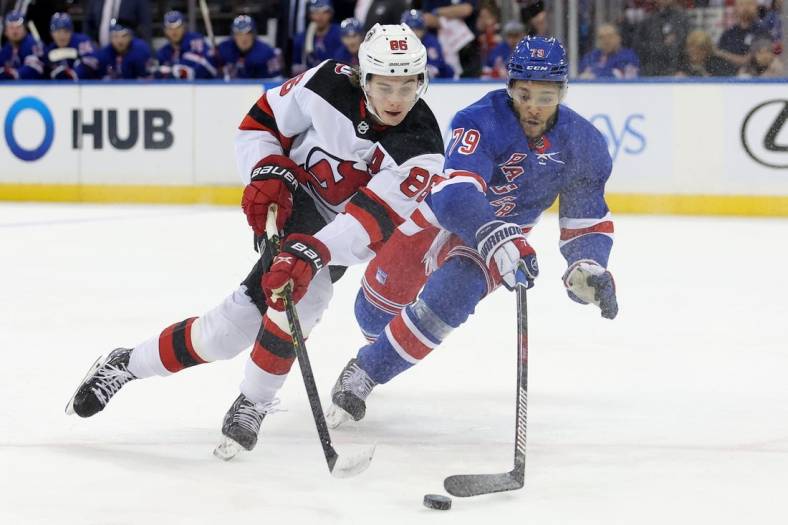 Dec 12, 2022; New York, New York, USA; New York Rangers defenseman K'Andre Miller (79) knocks the puck away from New Jersey Devils center Jack Hughes (86) during the first period at Madison Square Garden. Mandatory Credit: Brad Penner-USA TODAY Sports