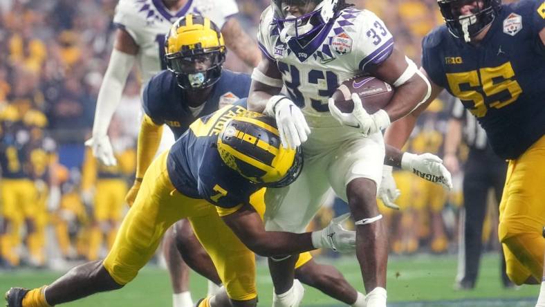 Dec 31, 2022; Glendale, Arizona, USA; TCU Horned Frogs running back Kendre Miller (33) tries to break away from Michigan Wolverines Makari Paige (7) past during the Vrbo Fiesta Bowl at State Farm Stadium. Mandatory Credit: Joe Rondone-Arizona Republic

Ncaa Fiesta Bowl Game