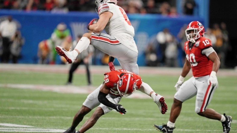 Dec 31, 2022; Atlanta, Georgia, USA; Ohio State Buckeyes tight end Cade Stover (8) goes airborne over Georgia Bulldogs defensive back Christopher Smith (29) during the first quarter of the 2022 Peach Bowl at Mercedes-Benz Stadium. Mandatory Credit: Dale Zanine-USA TODAY Sports