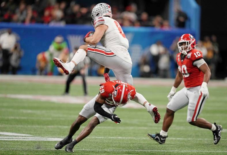 Dec 31, 2022; Atlanta, Georgia, USA; Ohio State Buckeyes tight end Cade Stover (8) goes airborne over Georgia Bulldogs defensive back Christopher Smith (29) during the first quarter of the 2022 Peach Bowl at Mercedes-Benz Stadium. Mandatory Credit: Dale Zanine-USA TODAY Sports