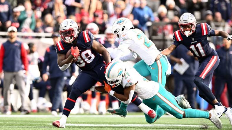 Jan 1, 2023; Foxborough, Massachusetts, USA; Miami Dolphins safety Eric Rowe (21) takles New England Patriots running back Rhamondre Stevenson (38) during the first half at Gillette Stadium. Mandatory Credit: Brian Fluharty-USA TODAY Sports