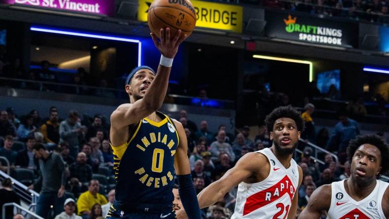 Jan 2, 2023; Indianapolis, Indiana, USA; Indiana Pacers guard Tyrese Haliburton (0) shoots the ball while Toronto Raptors forward Thaddeus Young (21)  defends in the second quarter at Gainbridge Fieldhouse. Mandatory Credit: Trevor Ruszkowski-USA TODAY Sports