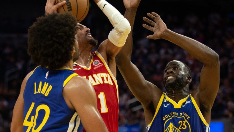 Jan 2, 2023; San Francisco, California, USA; Atlanta Hawks guard Trae Young (11) drives to the basket between Golden State Warriors forwards Anthony Lamb (40) and Draymond Green (23)  during the second quarter at Chase Center. Mandatory Credit: D. Ross Cameron-USA TODAY Sports