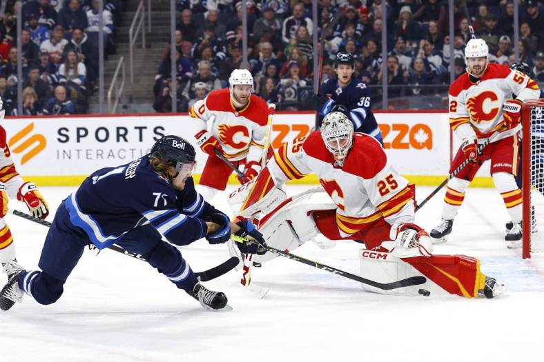 Jan 3, 2023; Winnipeg, Manitoba, CAN; Winnipeg Jets left wing Axel Jonsson-Fjallby (71) shoots on Calgary Flames goaltender Jacob Markstrom (25) in the second period at Canada Life Centre. Mandatory Credit: James Carey Lauder-USA TODAY Sports