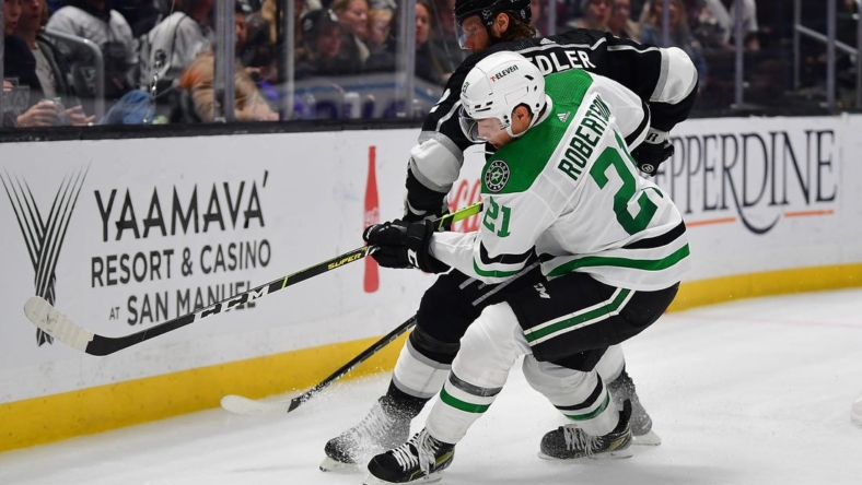 Jan 3, 2023; Los Angeles, California, USA; Dallas Stars left wing Jason Robertson (21) plays for the puck against Los Angeles Kings defenseman Alexander Edler (2) during the third period at Crypto.com Arena. Mandatory Credit: Gary A. Vasquez-USA TODAY Sports
