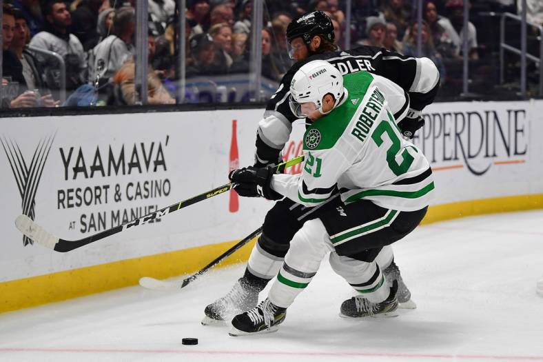 Jan 3, 2023; Los Angeles, California, USA; Dallas Stars left wing Jason Robertson (21) plays for the puck against Los Angeles Kings defenseman Alexander Edler (2) during the third period at Crypto.com Arena. Mandatory Credit: Gary A. Vasquez-USA TODAY Sports