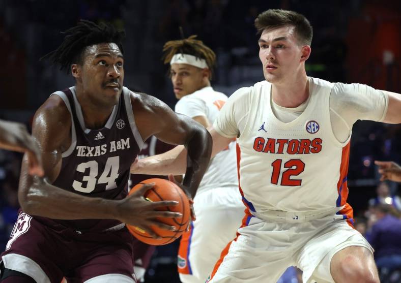 Jan 4, 2023; Gainesville, Florida, USA; Texas A&M Aggies forward Julius Marble (34) drives to the basket as Florida Gators forward Colin Castleton (12) defends during the first half at Exactech Arena at the Stephen C. O'Connell Center. Mandatory Credit: Kim Klement-USA TODAY Sports