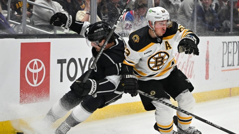 Jan 5, 2023; Los Angeles, California, USA;  Los Angeles Kings defenseman Sean Durzi (50) and Boston Bruins left wing Brad Marchand (63) battle for the puck along the boards in the first period at Crypto.com Arena. Mandatory Credit: Jayne Kamin-Oncea-USA TODAY Sports