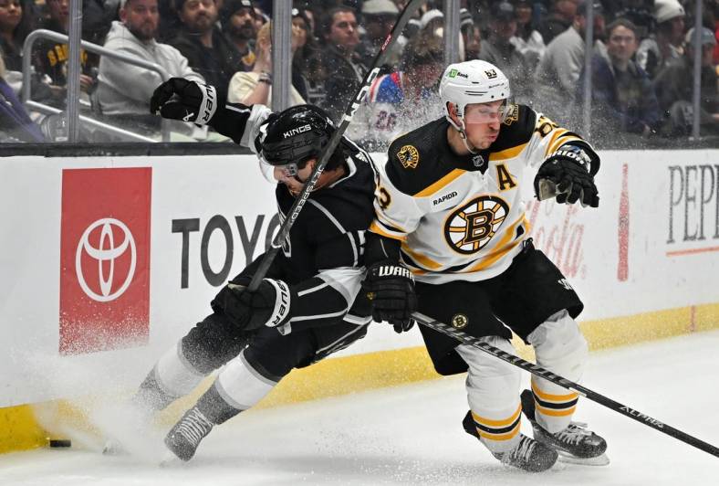 Jan 5, 2023; Los Angeles, California, USA;  Los Angeles Kings defenseman Sean Durzi (50) and Boston Bruins left wing Brad Marchand (63) battle for the puck along the boards in the first period at Crypto.com Arena. Mandatory Credit: Jayne Kamin-Oncea-USA TODAY Sports