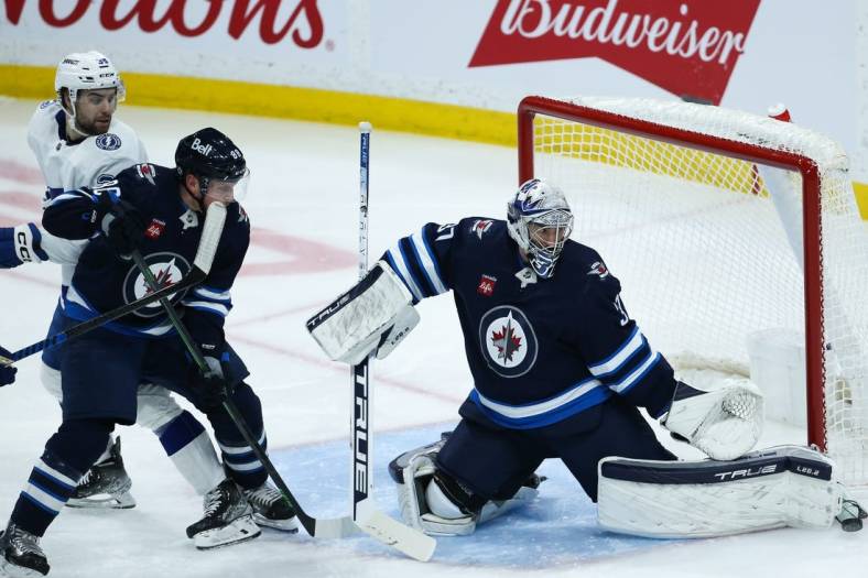 Jan 6, 2023; Winnipeg, Manitoba, CAN;  Winnipeg Jets goalie Connor Hellebuyck (37) makes a save as Winnipeg Jets defenseman Nate Schmidt (88) and Tampa Bay Lightning forward Brandon Hagel (38) look  for a rebound during the third period at Canada Life Centre. Mandatory Credit: Terrence Lee-USA TODAY Sports
